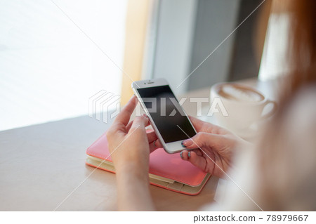 Female hands using mobile phone for organising schedule while drinking latte during the coffee break Female hands using mobile phone for organising schedule while drinking latte during the coffee break 78979667