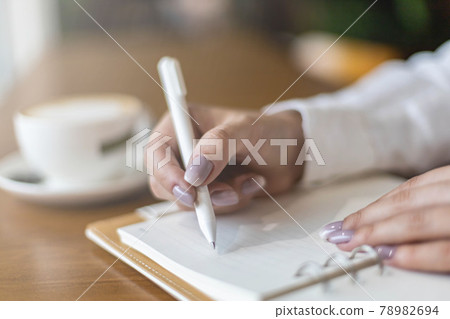 Closeup female hands making paper notes in notepad use pen table cafeteria writing diary, planning Closeup female hands making paper notes in notepad use pen table cafeteria writing diary, planning 78982694