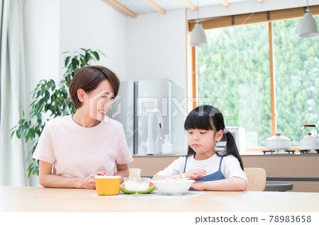 在廚房的桌子上，在媽媽旁邊吃飯的女孩 78983658