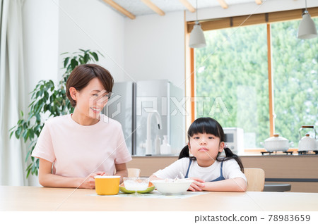 在廚房的桌子上,在媽媽旁邊吃飯的女孩 在廚房的桌子上,在媽媽旁邊吃飯的女孩 78983659
