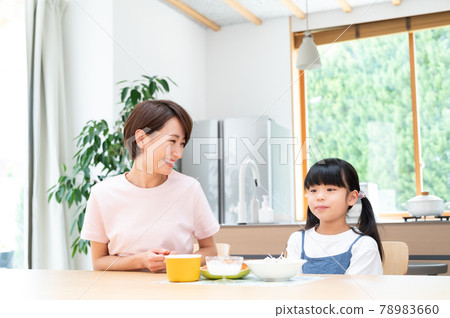 在廚房的桌子上,在媽媽旁邊吃飯的女孩 在廚房的桌子上,在媽媽旁邊吃飯的女孩 78983660
