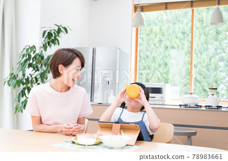在廚房的桌子上，在媽媽旁邊吃飯的女孩 78983661
