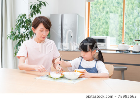 在廚房的桌子上,在媽媽旁邊吃飯的女孩 在廚房的桌子上,在媽媽旁邊吃飯的女孩 78983662
