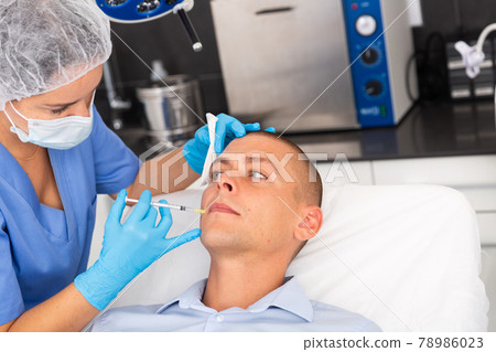 Man receiving cosmetic facial injection in clinic Man receiving cosmetic facial injection in clinic 78986023