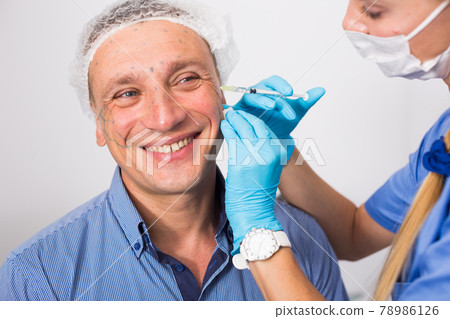 Female specialist is doing injection to client for anti-aging Female specialist is doing injection to client for anti-aging 78986126