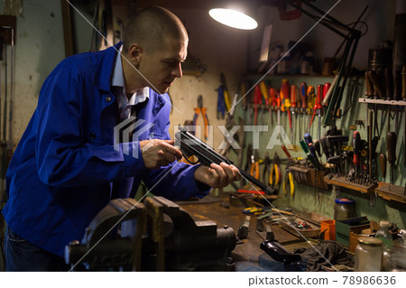 Skilled craftsman of weapons workshop repairing of small-bore handgun Skilled craftsman of weapons workshop repairing of small-bore handgun 78986636