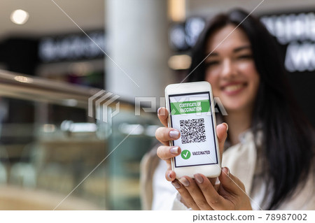 Portrait smiling woman posing with vaccine certificate on smartphone screen. Coronavirus prevention Portrait smiling woman posing with vaccine certificate on smartphone screen. Coronavirus prevention 78987002