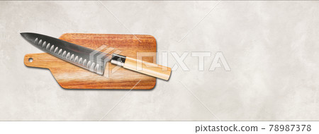 Traditional Japanese gyuto chief knife on a cutting board. White concrete background banner 78987378