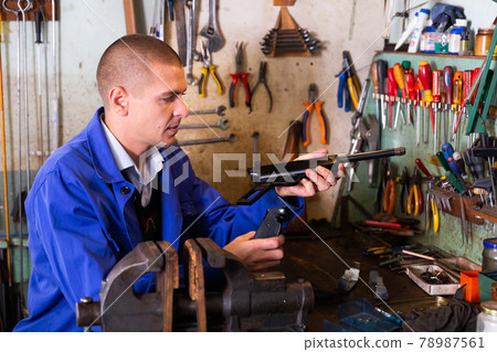 Gunsmith assembling smallbore sporting pistol in workshop 78987561