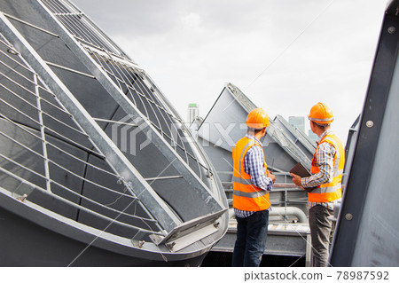 Asian male engineer inspecting pipe fittings and chillers, refrigeration plant refrigeration plant in  factory. male mechanic wearing helmet and Reflective Safety Vest uses laptop, tablet, equipment 78987592