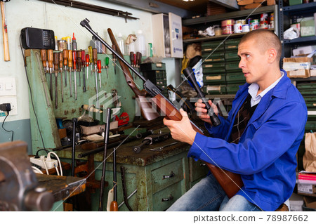 Gunsmith attaches a telescopic sight to rifle in weapons workshop Gunsmith attaches a telescopic sight to rifle in weapons workshop 78987662