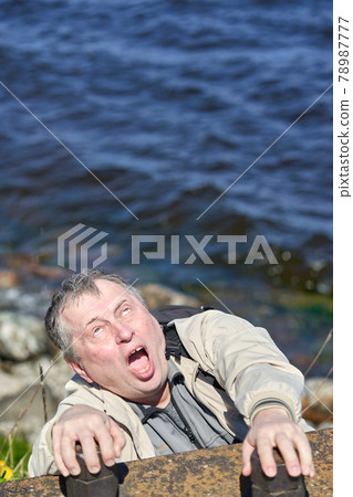 Freak clings his hands to the edge of the cliff above the water Freak clings his hands to the edge of the cliff above the water 78987777