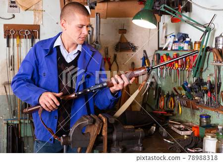 Gunsmith performing checkout of single-barrelled shotgun in weapons workshop Gunsmith performing checkout of single-barrelled shotgun in weapons workshop 78988318