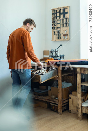 Male tanner working with handpress device machine cutting pattern on stuff material leather workshop 78988469