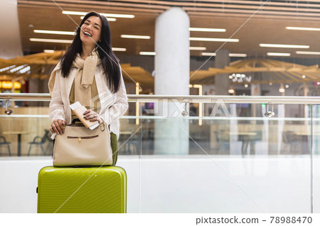 Happy woman traveler with documents and ticket waiting departure at international airport terminal Happy woman traveler with documents and ticket waiting departure at international airport terminal 78988470