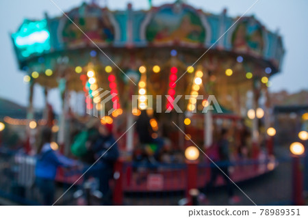A blurry colorful carousel in the amusement park at evening illumination. The effect of bokeh 78989351