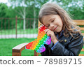 Caucasian little girl playing with pop it silicone trendy rainbow colow toy 78989715