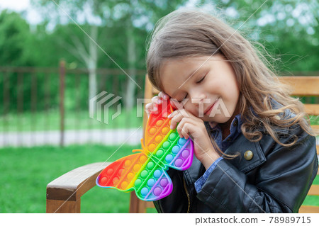 Caucasian little girl playing with pop it silicone trendy rainbow colow toy 78989715