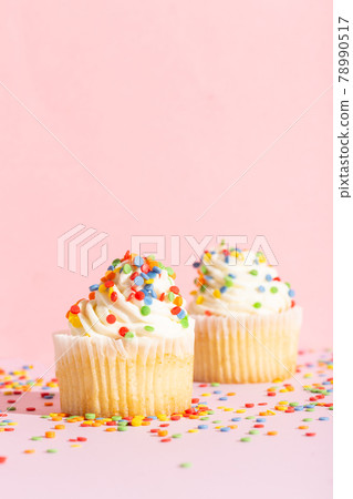 White cream cupcake with color sprinkles on rose White cream cupcake with color sprinkles on rose 78990517
