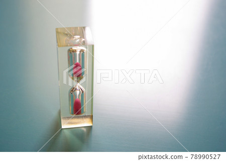 Acrylic hourglass with sand falling on the left side of the blue plastic sheet Acrylic hourglass with sand falling on the left side of the blue plastic sheet 78990527