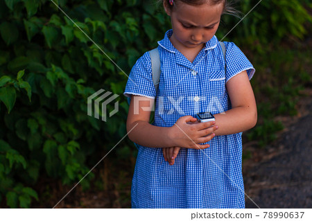 Kid using smartwatch outdoor. Child talking on the smartphone. Schoolgirl using touchscreen on watches browsing internet Kid using smartwatch outdoor. Child talking on the smartphone. Schoolgirl using touchscreen on watches browsing internet 78990637