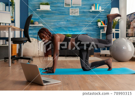 Black woman doing straight- leg donky kick pushing left foot up Black woman doing straight- leg donky kick pushing left foot up 78993315