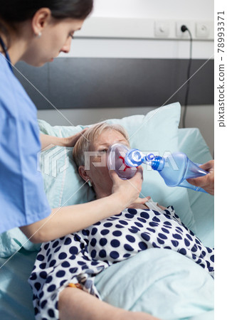 Doctor and nurse helping sick hospitalized senior woman breath 78993371
