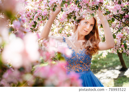 Red-haired woman on a background of pink flowers. Red-haired woman on a background of pink flowers. 78993522