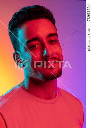 Close-up portrait of Latina young man isolated on gradient yellow purple background in neon light. Concept of emotions, facial expression 78993894