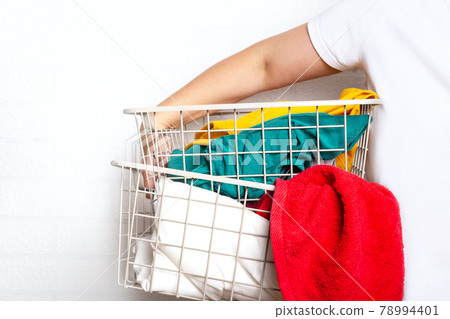 Woman with colourful clothes in laundry basket. 78994401
