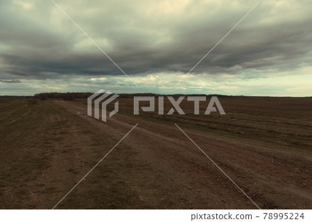 A dirt road among the fields in the evening. Autumn landscape. A dirt road among the fields in the evening. Autumn landscape. 78995224