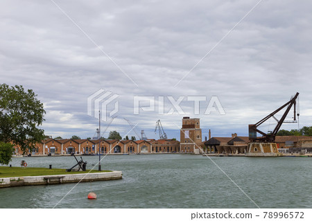Industrial shipyards (Arsenale di Venezia) in Italy, Venice. Loading cranes and docks. Cloudy, summer. Industrial shipyards (Arsenale di Venezia) in Italy, Venice. Loading cranes and docks. Cloudy, summer. 78996572