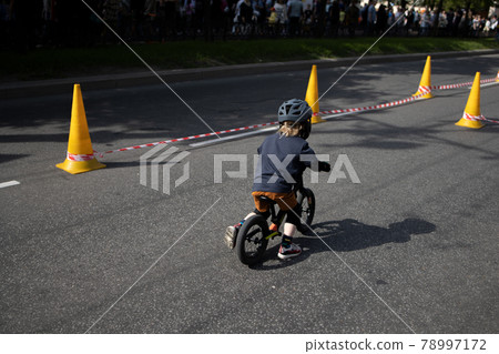 a child on a bicycle, goes around cones on the road a child on a bicycle, goes around cones on the road 78997172
