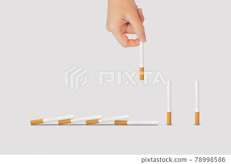 Hand holding and taking out cigarette piece from the row of cigarettes. Hand holding and taking out cigarette piece from the row of cigarettes. 78998586