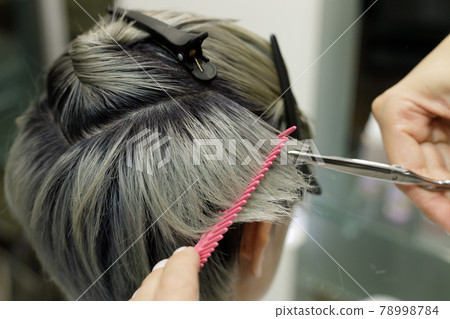 hairdresser hands with comb and scissors cut the model hair 78998784