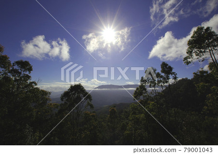 A refreshing, clear blue sky: a sunburst with intense light and a beautiful view of clouds spreading across the mountaintop. A refreshing, clear blue sky: a sunburst with intense light and a beautiful view of clouds spreading across the mountaintop. 79001043