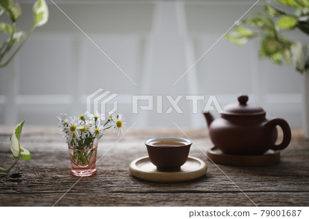 Oriental teapot and tea cup with daisy flower on wooden table Oriental teapot and tea cup with daisy flower on wooden table 79001687
