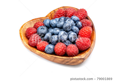 Raspberry and blueberry in wooden bowl in the shape of heart isolated on white background. 79001869