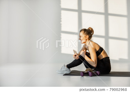 Woman with phone on a fitness training Woman with phone on a fitness training 79002968
