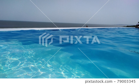 Infinity pool with blue water overlooking the sea Infinity pool with blue water overlooking the sea 79003345