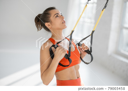 Woman training on TRX fitness straps Woman training on TRX fitness straps 79003458