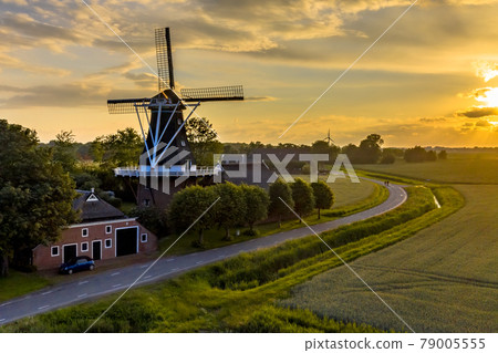 Historic windmill at a farm in agricultural landscape Historic windmill at a farm in agricultural landscape 79005555