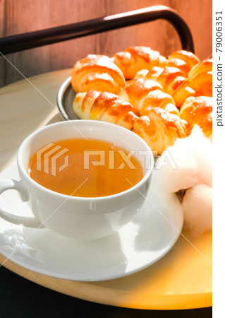 Traditional French croissants in a plate, cup of tea in background. Cotton branch. Selective focus. Homemade croissants Traditional French croissants in a plate, cup of tea in background. Cotton branch. Selective focus. Homemade croissants 79006351