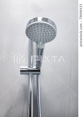 Shower head on a gray microcement wall of a modern bathroom 79006433