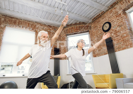 Two elderly people standing in yoga asana pose at home Two elderly people standing in yoga asana pose at home 79006557
