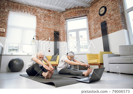 Retired couple using laptop while doing stretching exercises 79006573