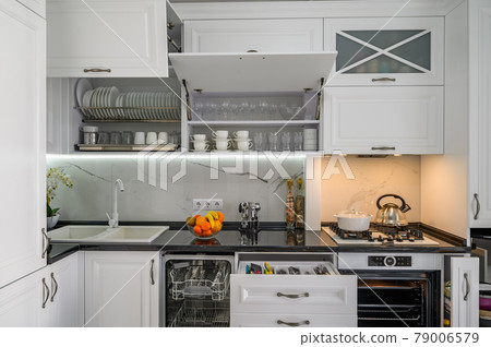 Luxurious white modern kitchen interior, drawers pulled out, dishwasher's door open 79006579