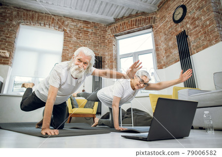 Happy aged couple training at home and using laptop Happy aged couple training at home and using laptop 79006582
