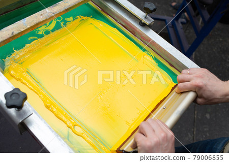 Serigraphy silk screen print process at clothes factory. Frame, squeegee and plastisol color paints Serigraphy silk screen print process at clothes factory. Frame, squeegee and plastisol color paints 79006855