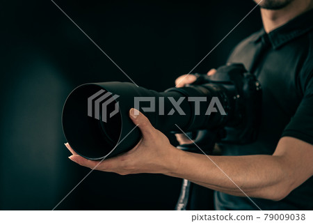 一位攝影師拿著帶超長焦鏡頭的相機 79009038